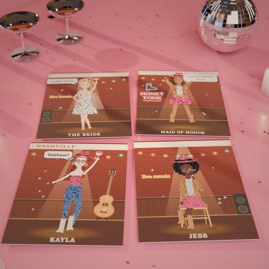 Four finished rhinestone canvases of a bachelorette crew on a marble table